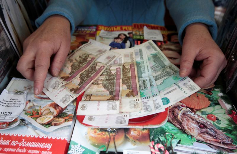 &copy; Reuters. FILE PHOTO: The vendor of a newspaper and magazine stall demonstrates rouble banknotes in Stavropol, southern Russia, January 21, 2016. REUTERS/Eduard Korniyenko/File Photo