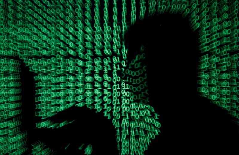 &copy; Reuters. FILE PHOTO: A man holds a laptop computer as cyber code is projected on him in this illustration picture taken on May 13, 2017. REUTERS/Kacper Pempel/Illustration