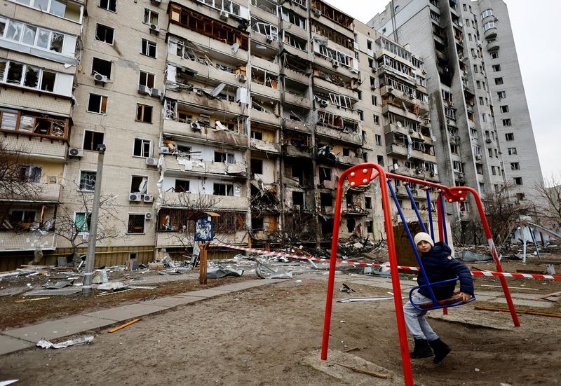 &copy; Reuters. Criança em balanço em frente a prédio residencial danificado em Kiev após Rússia lançar ataque maciço à capital ucraniana
25/02/2022 REUTERS/Umit Bektas