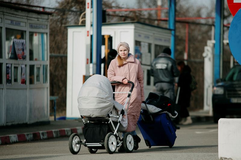 &copy; Reuters. Una mujer empuja un cochecito mientras lleva equipaje a través de la frontera de Ucrania a Rumania, en el punto de aduana Sighetu Marmatiei, en Baia Mare, Rumania. 25 de febrero de 2022. Inquam Photos/Paul Ursachi vía REUTERS