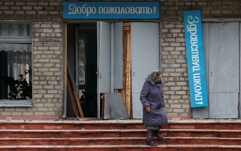 &copy; Reuters. Mulher caminha em frente a prédio de escola danificado na cidade de Horlivka, na região separatista ucraniana de Donetsk
25/02/2022 REUTERS/Alexander Ermochenko