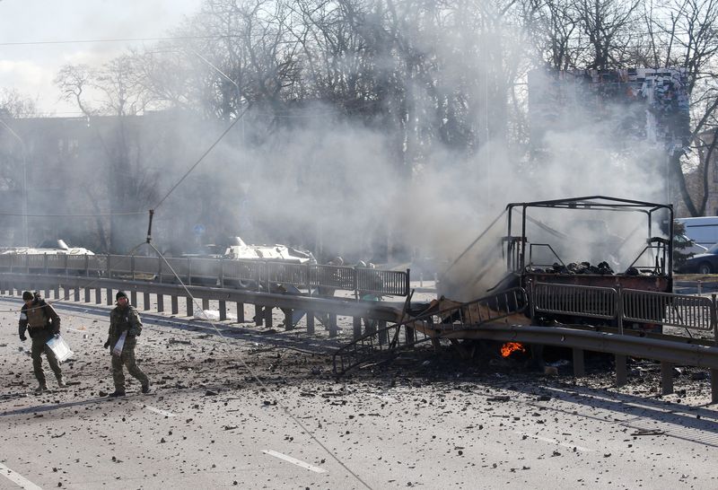 &copy; Reuters. Des militaires ukrainiens près d'un véhicule endommagé sur le site de combats avec les troupes russes à Kiev. Le président ukrainien a annoncé samedi que la capitale était toujours sous le contrôle des forces ukrainiennes après l'invasion militai
