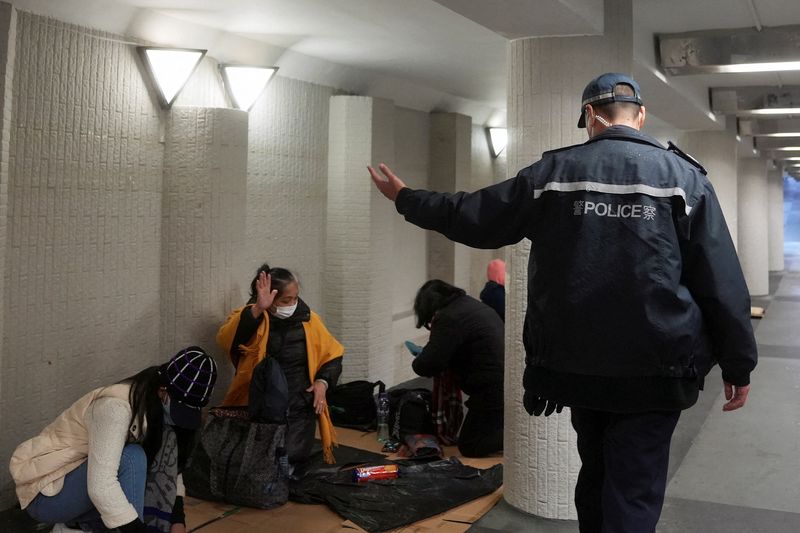 &copy; Reuters. FILE PHOTO: A police officer instructs domestic workers gathering on their rest day to leave, during a coronavirus disease (COVID-19) outbreak in Hong Kong, China February 20, 2022. REUTERS/Lam Yik/File Photo