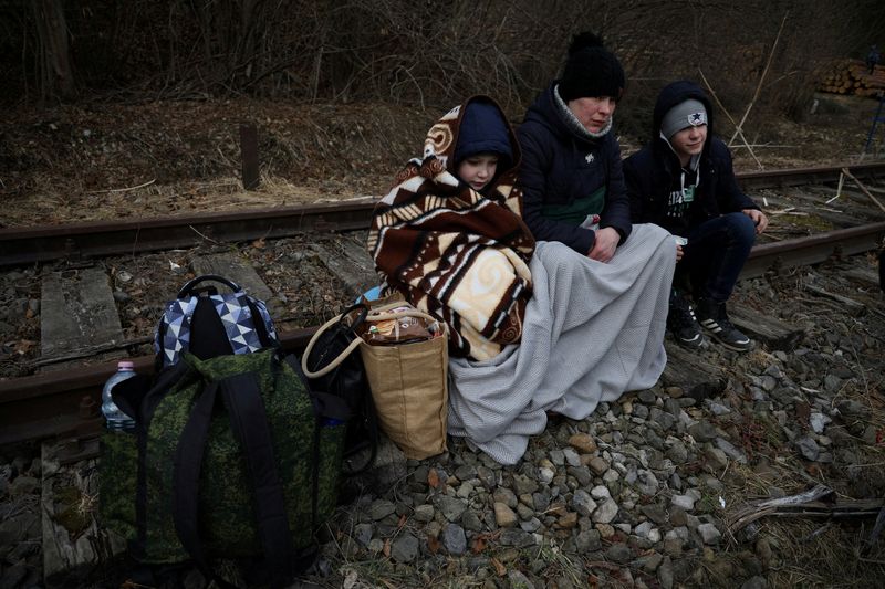 &copy; Reuters. FILE PHOTO: People sit on the railway after crossing the border between Poland and Ukraine, after Russia launched a massive military operation against Ukraine, in Kroscienko, Poland February 27, 2022. REUTERS/Kacper Pempel/File Photo