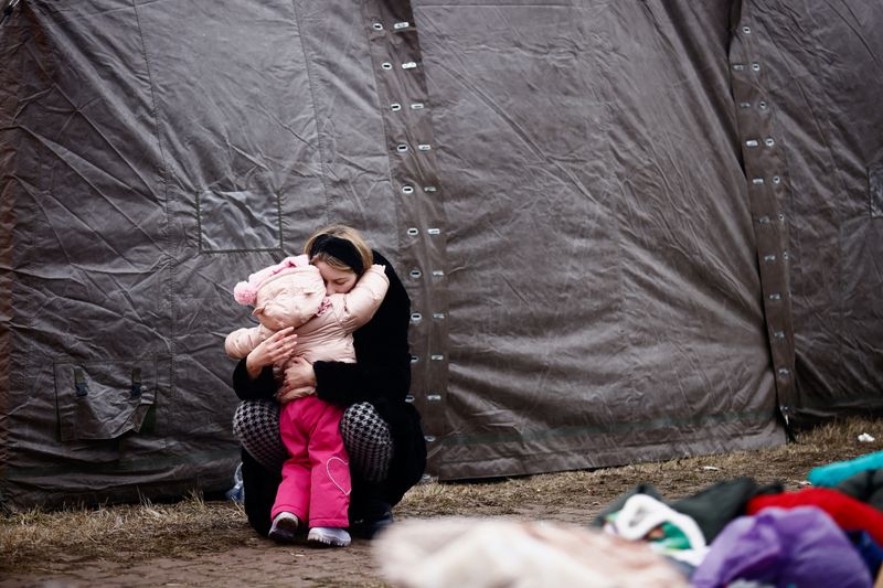 &copy; Reuters. Une femme fuyant l'invasion russe de l'Ukraine embrasse un enfant dans un camp temporaire à Przemyśl, Pologne. Des discussions ont démarré lundi à la frontière biélorusse entre une délégation ukrainienne et des représentants russes, cinq jours a