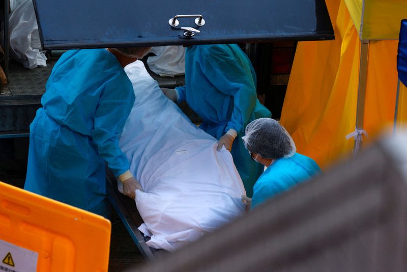 &copy; Reuters. Foto de archivo de empleados de una funeraria moviendo un cuerpo en una zona especial para el tratamiento del COVID en un hospital en Hong Kong
Feb 27, 2022. REUTERS/Tyrone Siu