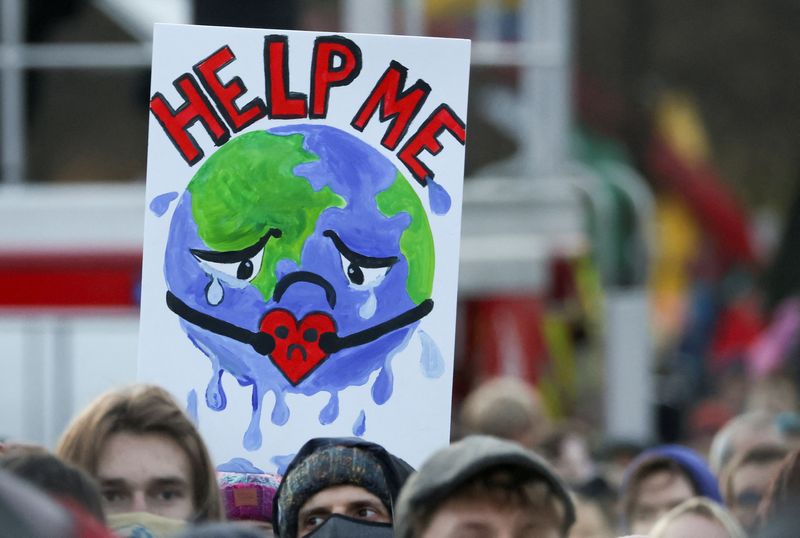 &copy; Reuters. FILE PHOTO: People carry a sign as they attend a protest during the UN Climate Change Conference (COP26), in Glasgow, Scotland, Britain, November 6, 2021. REUTERS/Yves Herman/File Photo