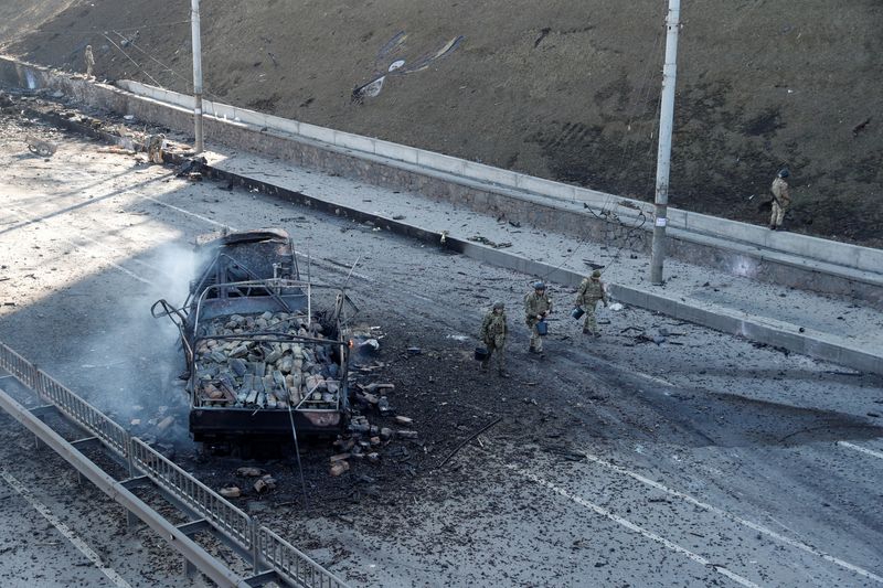 &copy; Reuters. جنود أوكرانيون يسيرون قرب مركبة مدمرة في موقع معارك مع القوات الروسية في 26 فبراير شباط 2022. تصوير فالنتاين اوجيرينكو- رويترز.