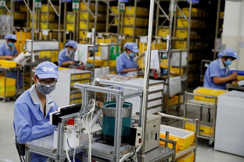 &copy; Reuters. FOTO DE ARCHIVO: Empleados con mascarillas trabajan en una fábrica del fabricante de componentes SMC en Pekín, China, 13 de mayo de 2020. REUTERS/Thomas Peter