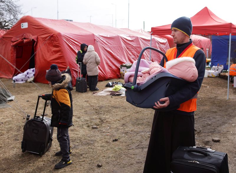 &copy; Reuters. قس متطوع يحمل رضيعا داخل مأوى مؤقت للاجئين الأوكرانيين في سلوفاكيا يوم الثلاثاء. رويترز