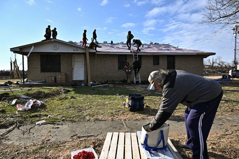 &copy; Reuters. FILE PHOTO: Charles Carmickle reaches to grab sandwiches to give away to nearby construction workers repairing a home after tornadoes ripped through several U.S. states in December in Mayfield, Kentucky, U.S., January 28, 2022. REUTERS/Jonathan Cherry