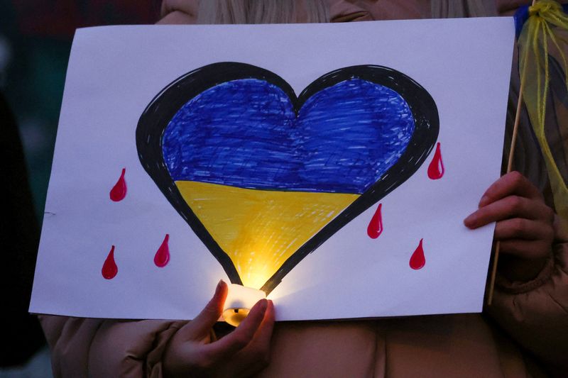 &copy; Reuters. Una persona sostiene una vela frente a un dibujo de un corazón con los colores de la bandera de Ucrania, en Liverpool, Inglaterra, Marzo 1, 2022. REUTERS/Phil Noble
