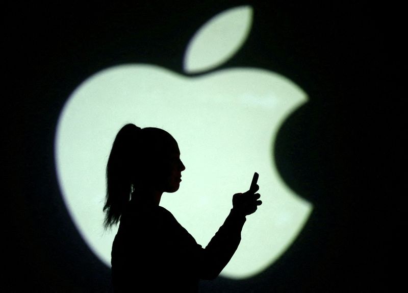 © Reuters. FILE PHOTO: Silhouette of mobile user is seen next to a screen projection of Apple logo in this picture illustration taken March 28, 2018.  REUTERS/Dado Ruvic/Illustration