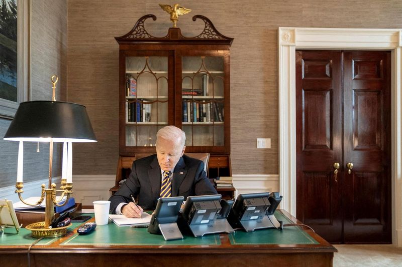 &copy; Reuters. U.S. President Joe Biden writes at his desk in The White House in Washington, U.S., March 1, 2022. The White House/Handout via REUTERS 