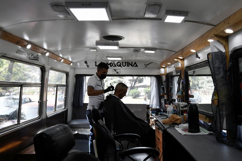 &copy; Reuters. FILE PHOTO: Franklin Iriarte gives a haircut to a customer at his barbershop, which he installed inside a bus, in La Guaira, Venezuela Februrary 17, 2022. REUTERS/Gaby Oraa