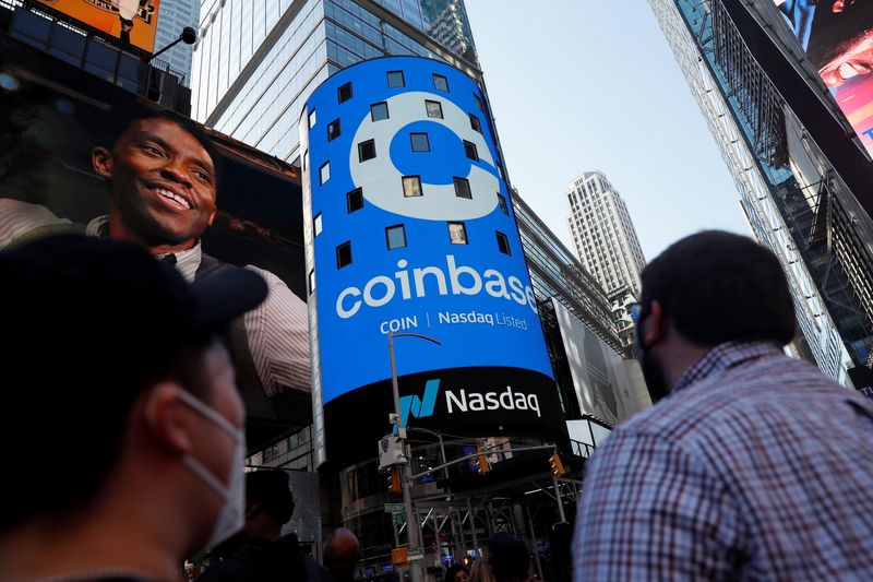 &copy; Reuters. La gente guarda mentre il logo di Coinbase Global Inc, il più grande scambio di criptovalute degli Stati Uniti, viene visualizzato sul jumbotron del Nasdaq MarketSite a Times Square. New York 14 aprile 2021. REUTERS/Shannon Stapleton