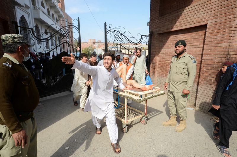 &copy; Reuters. أحد المصابين في تفجير مسجد بباكستان أثناء نقله إلى مستشفى في بيشاور يوم الجمعة. تصوير: خورام بارفيز - رويترز. 