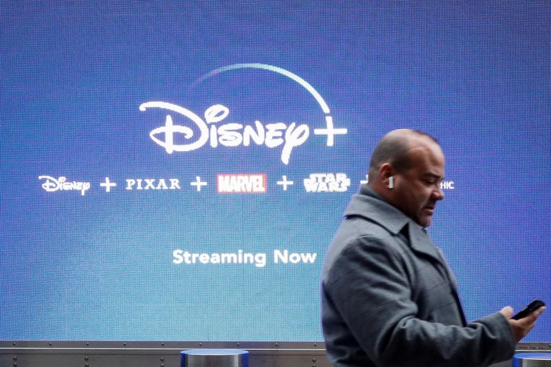 &copy; Reuters. FOTO DE ARCHIVO. Un hombre mira su teléfono mientras pasa junto a una pantalla que anuncia el servicio de streaming de Walt Disney, Disney+, en Nueva York, Estados Unidos. 12 de noviembre de 2019. REUTERS/Brendan McDermid