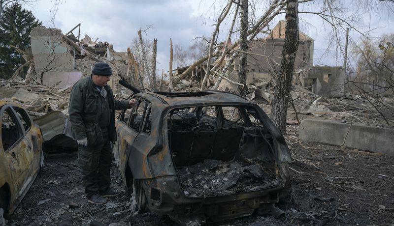 © Reuters. رجل يقف بجوار سيارة محترقة في اقليم كييف الاوكراني يوم الجمعة. تصوير: مكسيم ليفين - رويترز.