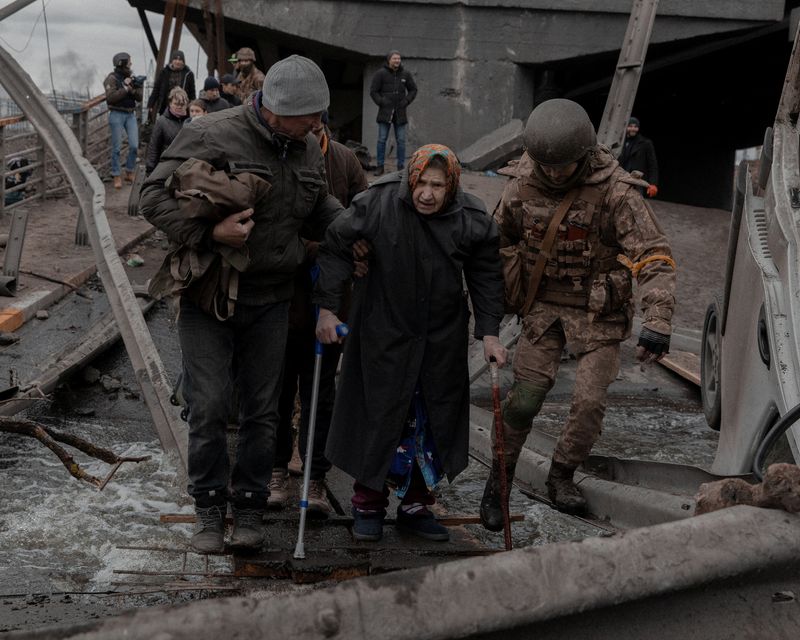 &copy; Reuters. An elderly woman is helped while crossing a destroyed bridge as she tries to leave the city of Irpin, in the Kyiv region, Ukraine March 5, 2022. Jedrzej Nowicki/Agencja Wyborcza.pl via REUTERS 