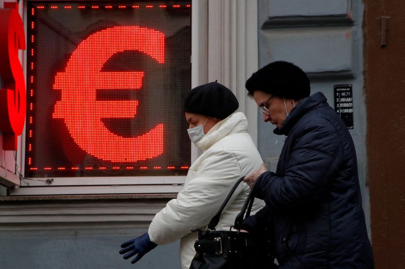 &copy; Reuters. Passanti davanti a una cartello che mostra i simboli del dollaro e dell'euro a San Pietroburgo, Russia, 25 febbraio 2022. REUTERS/Anton Vaganov 
