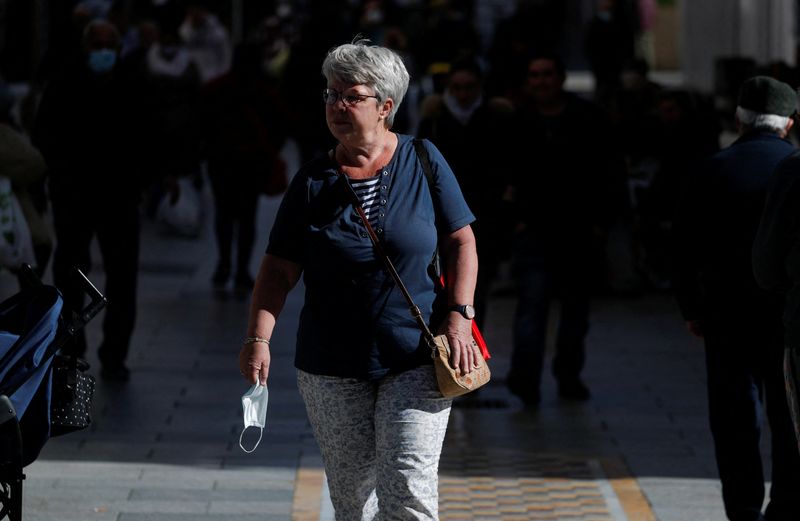 &copy; Reuters. FOTO DE ARCHIVO: Una mujer camina con una mascarilla en la mano por una calle de Ronda, provincia de Málaga, Andalucía, España, el 10 de febrero de 2022. REUTERS/Jon Nazca.