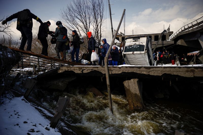 &copy; Reuters. Personas cruzan debajo de un puente destruido mientras huyen del avance de las tropas rusas cuyo ataque contra Ucrania continúa en la ciudad de Irpin en las afueras de Kiev, Ucrania, el 8 de marzo de 2022. REUTERS/Thomas Peter
