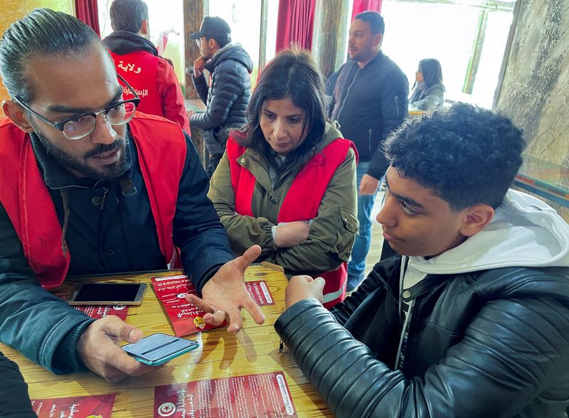 &copy; Reuters. Ahmed Kouki, a pro-Saied volunteer, introduces to students an online multiple-choice questionnaire that President Kais Saied has set up as a part of a 'consultation' before he rewrites the constitution, in Tunis, Tunisia February 28, 2022. Picture taken F