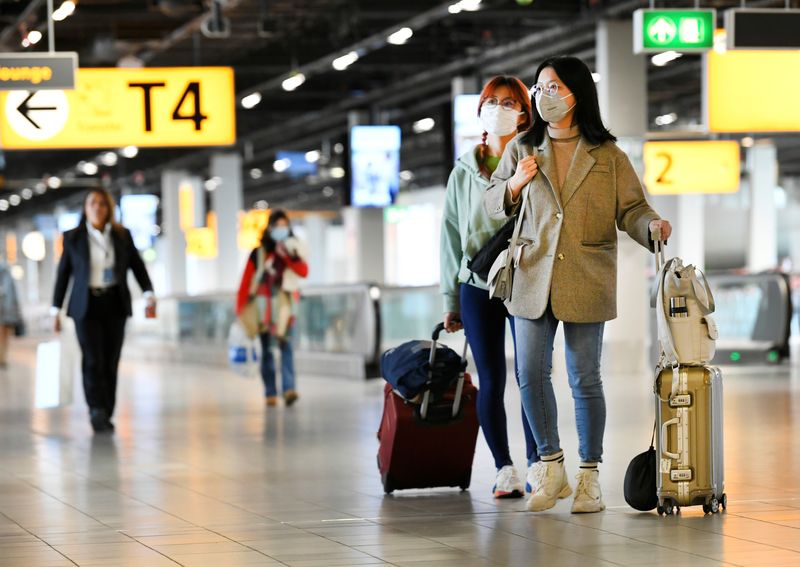 &copy; Reuters. People wearing protective face masks stand, as Schiphol Airport reduces its flights due to the coronavirus disease (COVID-19) outbreak, in Amsterdam, Netherlands April 2, 2020. REUTERS/Piroschka van de Wouw