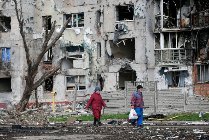 &copy; Reuters. Pessoas caminham em frente a prédio residencial destruído em Mariupol, na Ucrânia
22/04/2022
REUTERS/Alexander Ermochenko