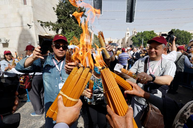 © Reuters. مصلون يحضرون مراسم النار المقدسة خارج كنيسة المهد في بيت لحم في الضفة الغربية المحتلة يوم السبت. تصوير: موسى قواسمة-رويترز. 