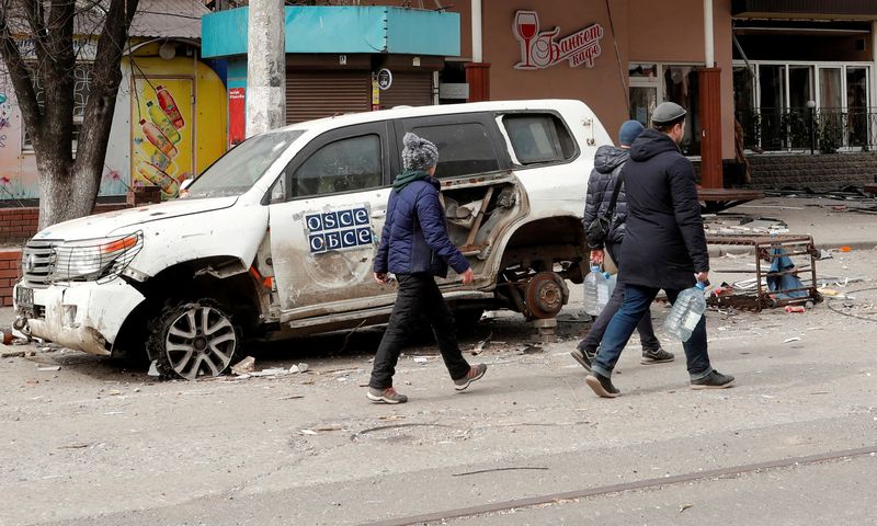 &copy; Reuters. FILE PHOTO: People walk past an OSCE car damaged in the course of Ukraine-Russia conflict in the southern port city of Mariupol, Ukraine April 1, 2022. REUTERS/Alexander Ermochenko/File Photo