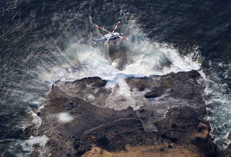 © Reuters. An aerial view shows a Japan Coast Guard helicopter conducts a search and rescue operations for missing people boarded on the missing tour boat 