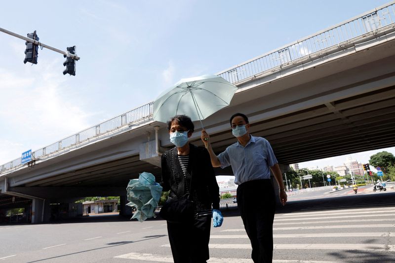 &copy; Reuters. شخصان يضعان كمامتين يعبران أحد الطرق في بكين يوم 25 مايو أيار 2022. تصوير: كارلوس جارسيا راولينز - رويترز