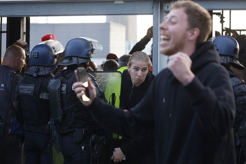 © Reuters. Soccer Football - Champions League Final - Liverpool v Real Madrid - Stade de France, Saint-Denis near Paris, France - May 28, 2022  A fan pushes through a police officer inside the stadium as the match is delayed REUTERS/Gonzalo Fuentes