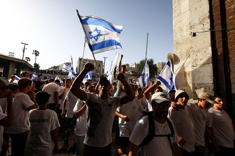 © Reuters. Israelis dance and sing while they hold Israeli national flags by Damascus Gate to Jerusalem's Old city May 29, 2022. REUTERS/ Ronen Zvulun