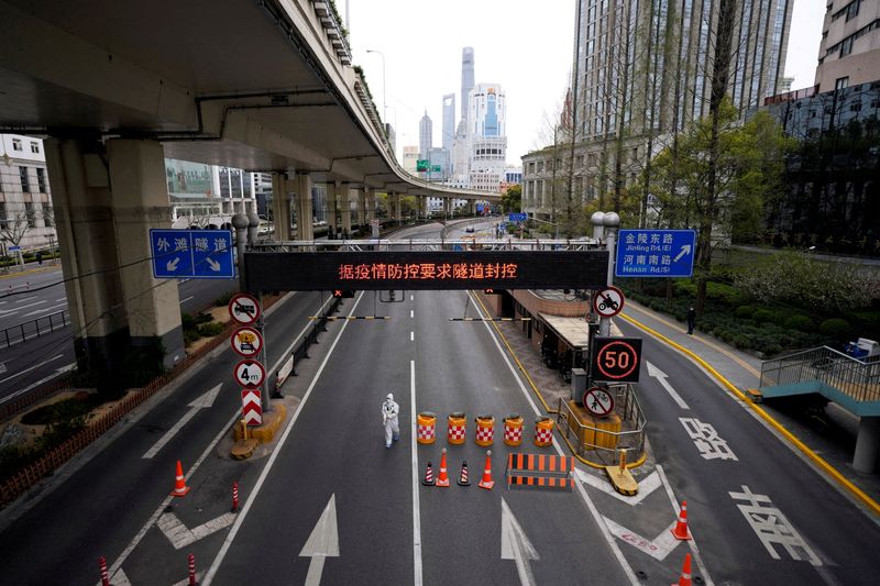 &copy; Reuters. FILE PHOTO: A worker in a protective suit walks at an entrance to a tunnel leading to the Pudong area across the Huangpu river amid the lockdown to contain the spread of the coronavirus disease (COVID-19) in Shanghai, China March 28, 2022. REUTERS/Aly Son