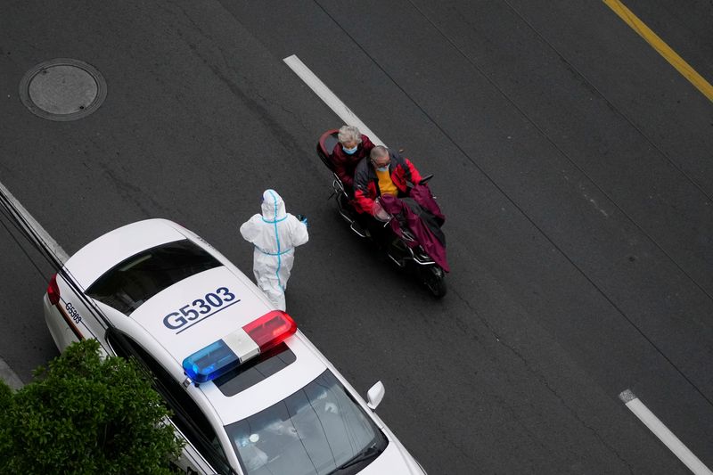 &copy; Reuters. FILE PHOTO: A man rides a vehicle carrying a woman past a police car outside a residential compound, during a lockdown to curb the spread of the coronavirus disease (COVID-19) in Shanghai, China April 5, 2022. REUTERS/Aly Song