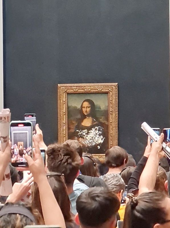 &copy; Reuters. زوار يلتقطون صورا ومقاطع فيديو للوحة الموناليزا بعد تلطيخ الزجاج الذي يحمي اللوحة بالقشدة في متحف اللوفر بباريس يوم الأحد. صورة لرويترز من 