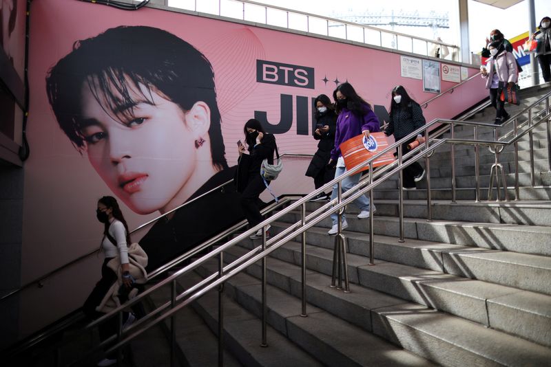 &copy; Reuters. FILE PHOTO: Fans of K-pop boy band BTS walk past an advertisement promoting their concert at Seoul Olympic stadium in Seoul, South Korea, March 10, 2022. REUTERS/Kim Hong-Ji