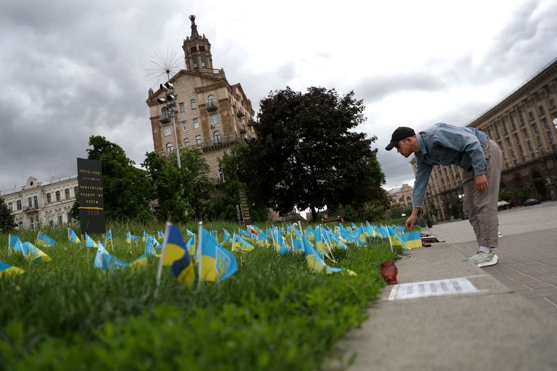 &copy; Reuters. Un habitant place un drapeau sur un lieu de mémoire improvisé, à Kiev. L'Ukraine a identifié plus de 600 suspects de crimes de guerre russes et a commencé à poursuivre environ 80 d'entre eux, a déclaré mardi la procureure générale. /Photo prise 