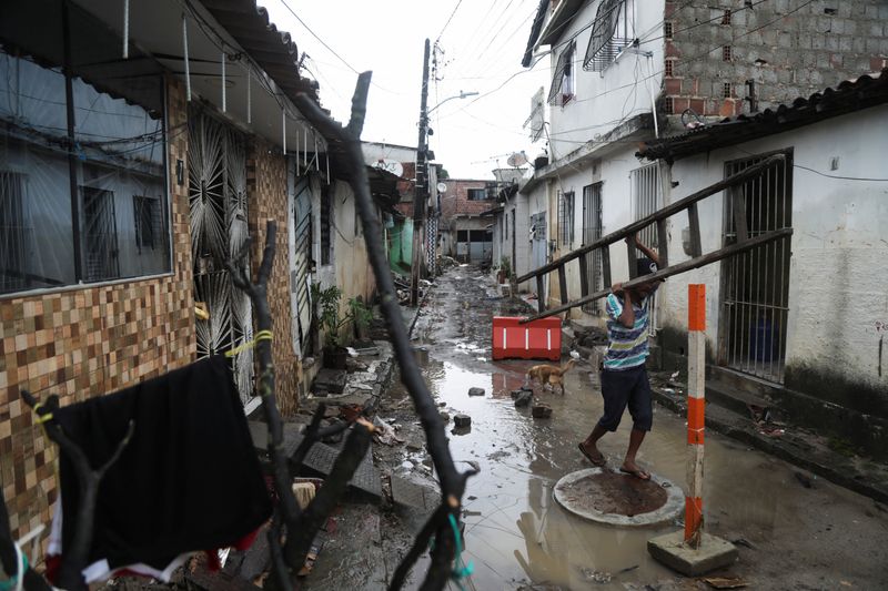 &copy; Reuters. Un hombre lleva una escalera entre los escombros de las casas dañadas por las fuertes lluvias, en el barrio de Coqueiral, en Recife, Brasil. 31 de mayo, 2022. REUTERS/Diego Nigro.