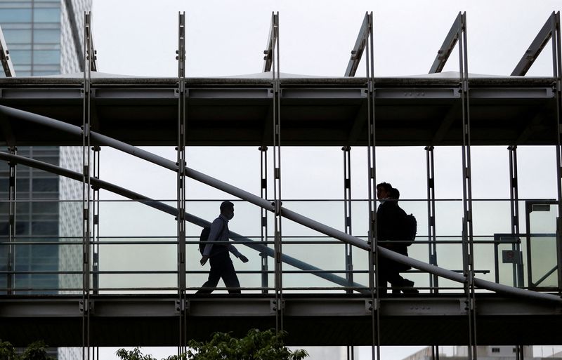 &copy; Reuters. FILE PHOTO: Businessmen wearing protective face masks walk on a pedestrian bridge, amid the spread of the coronavirus disease (COVID-19), in a business district in Tokyo, Japan June 24, 2020. REUTERS/Issei Kato/File Photo