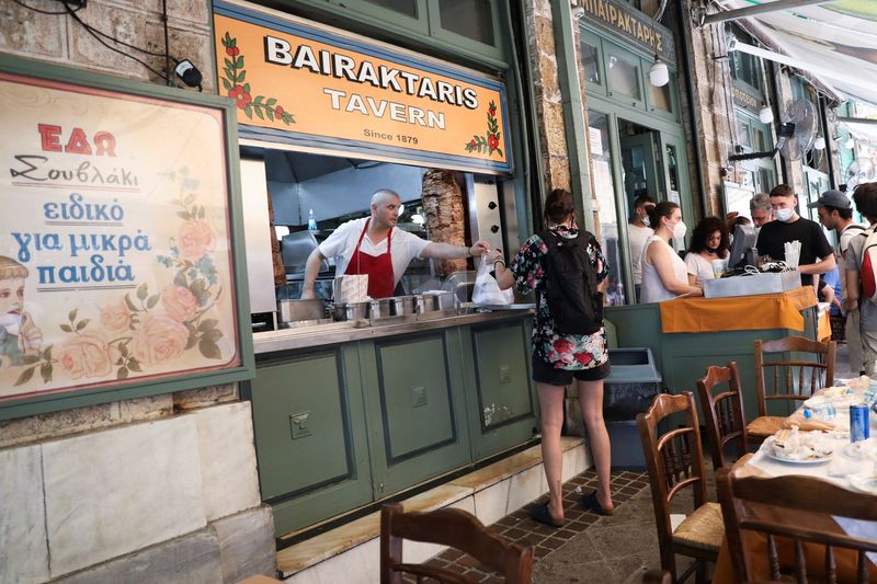 &copy; Reuters. A cook gives a customer a souvlaki, a popular Greek fast food made with pieces of meat grilled on a skewer, in a restaurant, in Athens, Greece, May 27, 2022. REUTERS/Louiza Vradi