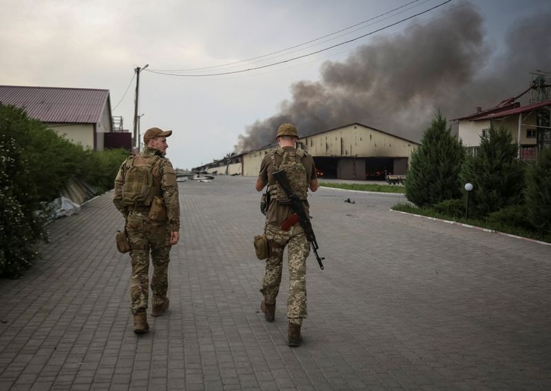 &copy; Reuters. جنديان أوكرانيان يسيران أمام صومعة حبوب محترقة بعد قصفها مرارا من قبل القوات الروسية في منطقة دونيتسك بأوكرانيا يوم الثلاثاء. تصوير: سيرهي 