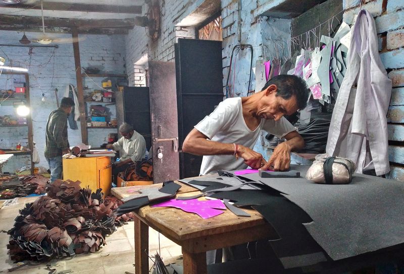 &copy; Reuters. Ashok Kumar, a worker, cuts synthetic leather to make shoes at the Vansh Foot Fashion, a small shoe making factory, in Agra, India, May 30, 2022. REUTERS/Manoj Kumar