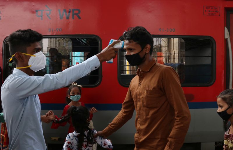 &copy; Reuters. موظف رعاية صحية يتحقق من درجة حرارة أحد الركاب لدى وصوله محطة السكك الحديدية في مومباي بالهند يوم 29 نوفمبر تشرين الثاني 2021. تصوير: نيهاريكا ك
