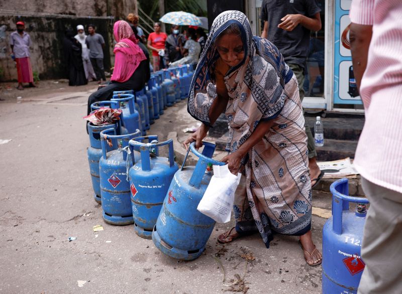&copy; Reuters. FILE PHOTO: A woman moves a gas tank as she stands in line to buy another tank near a distributor, amid the country's economic crisis, in Colombo, Sri Lanka, June 1, 2022. REUTERS/Dinuka Liyanawatte