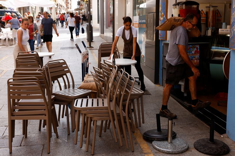 © Reuters. Waitresses prepare the terrace of an ice cream shop as a delivery man carries a sack of sugar in downtown Ronda, southern Spain June 2, 2022. REUTERS/Jon Nazca