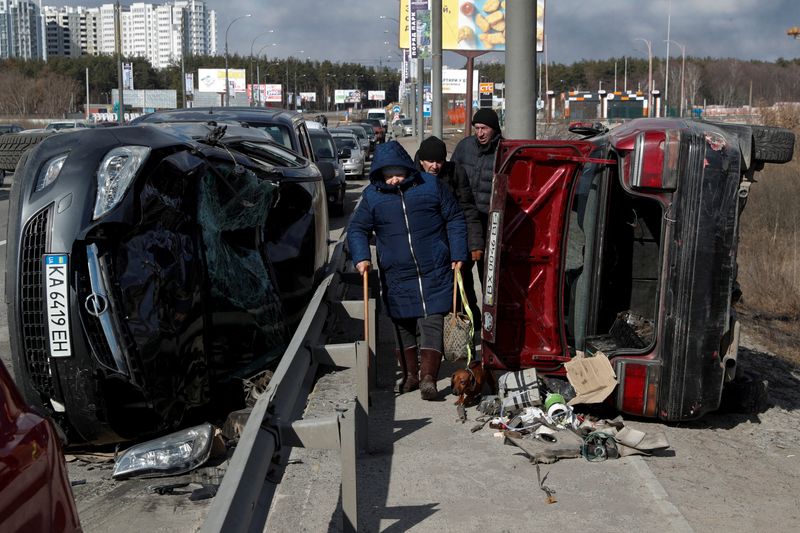 &copy; Reuters. FILE PHOTO: People walk between destroyed cars as they evacuate from the Irpin town, as Russia's attack on Ukraine continues, outside of Kyiv, Ukraine March 10, 2022.  REUTERS/Valentyn Ogirenko